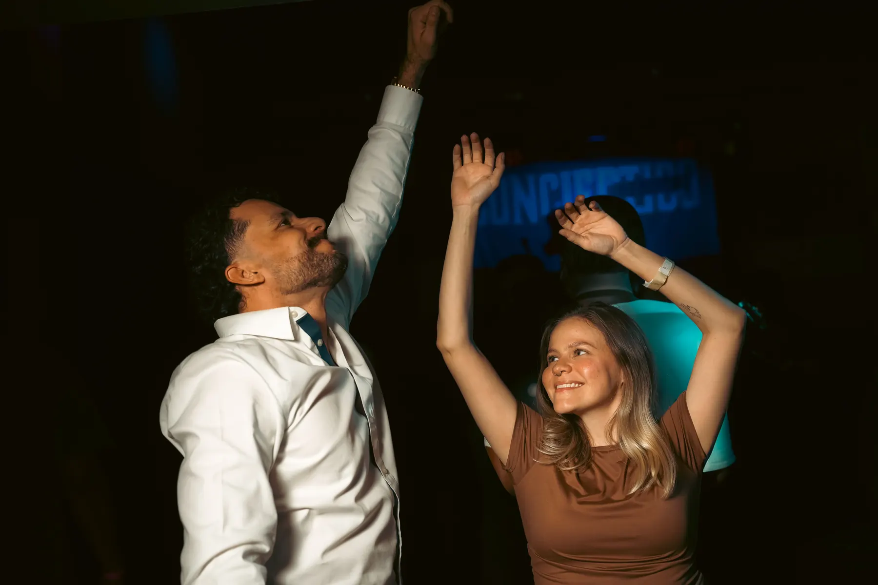 Pareja baila en una discoteca con los brazos arriba