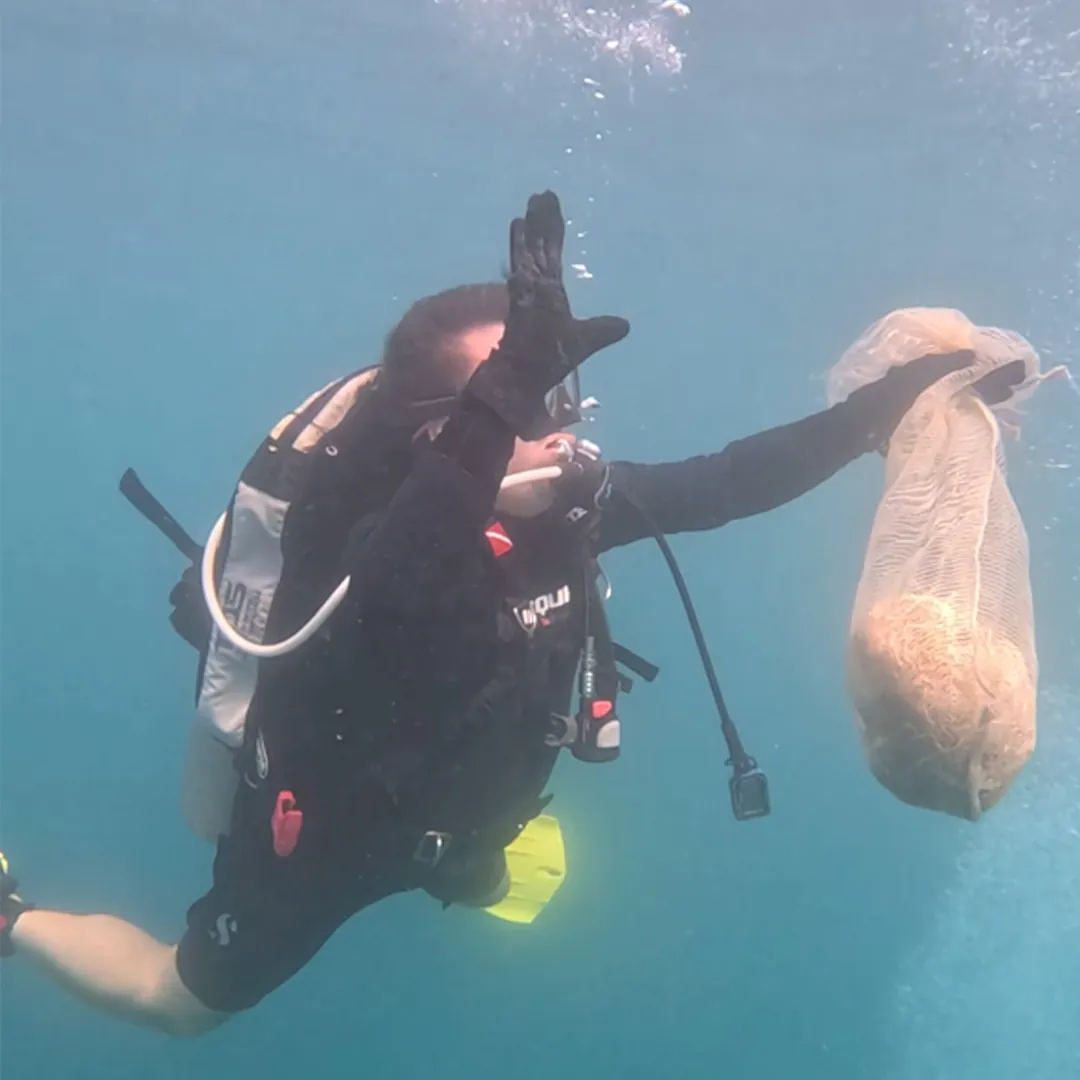 Buzo de la Fundación Save a Playa levanta una bolsa de malla con plástico recogido